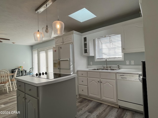 kitchen featuring a center island, sink, hanging light fixtures, white appliances, and white cabinets