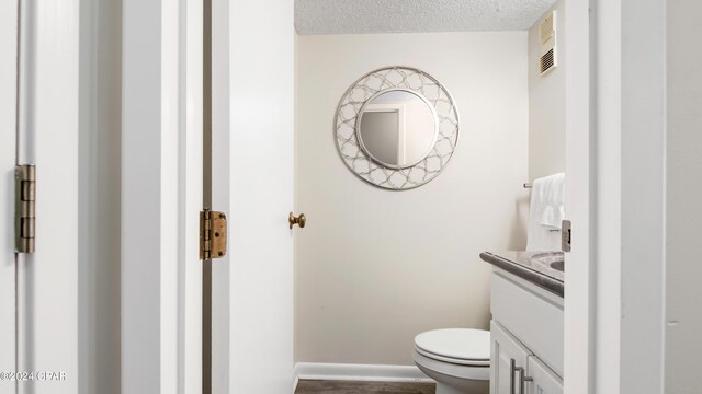 bathroom featuring vanity, toilet, and a textured ceiling