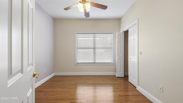 unfurnished bedroom with a ceiling fan, wood finished floors, baseboards, and a closet