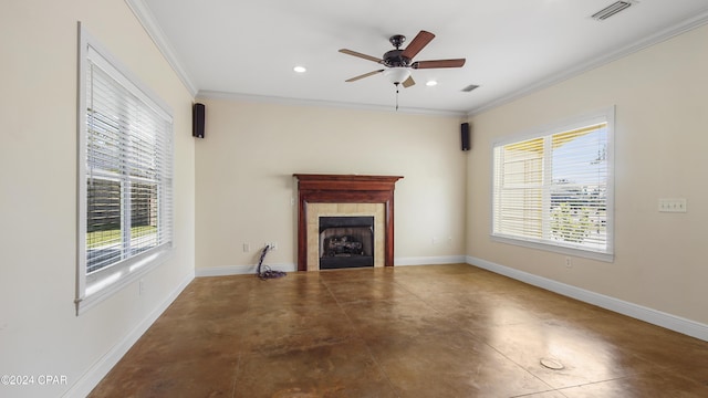 unfurnished living room featuring crown molding, ceiling fan, a healthy amount of sunlight, and a tiled fireplace