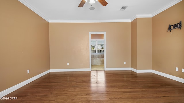 spare room featuring visible vents, baseboards, ornamental molding, wood finished floors, and a ceiling fan