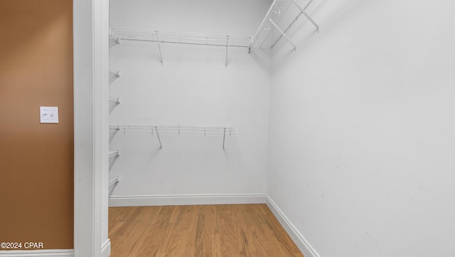 walk in closet with wood finished floors