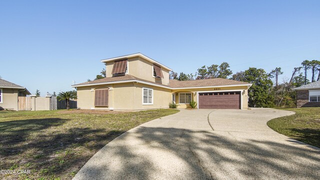 view of front of house with fence, driveway, an attached garage, stucco siding, and a front lawn