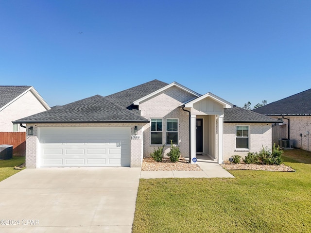 view of front of house with cooling unit, a garage, and a front lawn