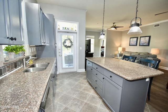 kitchen featuring a center island, sink, a kitchen breakfast bar, decorative light fixtures, and ornamental molding