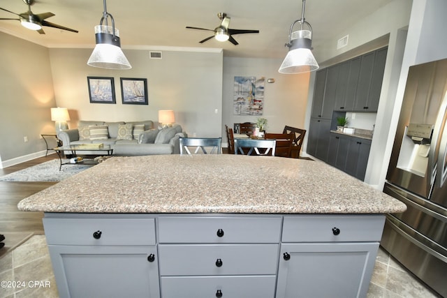 kitchen with a center island, crown molding, stainless steel refrigerator with ice dispenser, ceiling fan, and decorative light fixtures