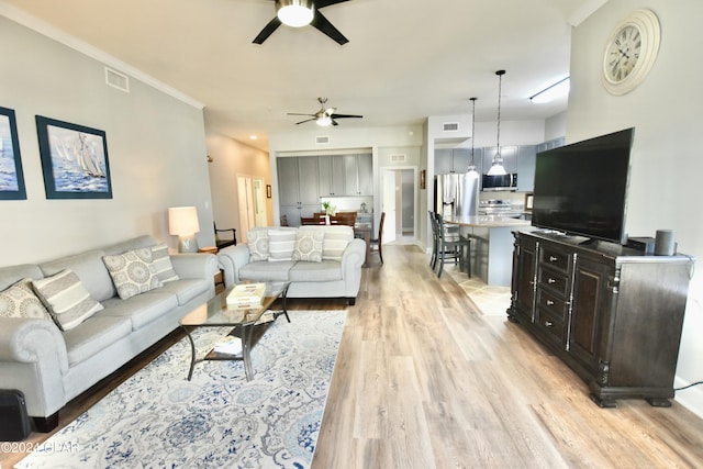 living room with light hardwood / wood-style floors, ceiling fan, and ornamental molding