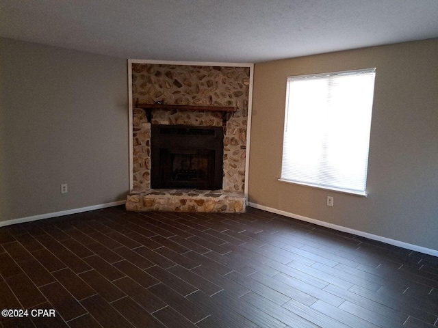 unfurnished living room featuring a fireplace, dark wood-type flooring, and a textured ceiling