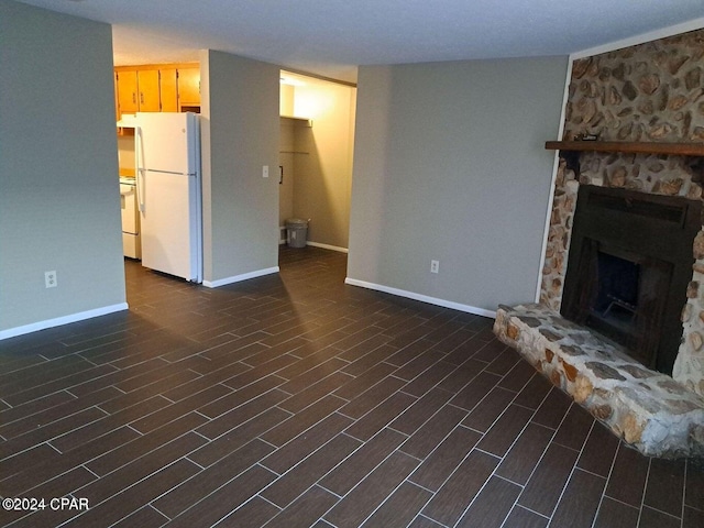 unfurnished living room with a stone fireplace and dark wood-type flooring