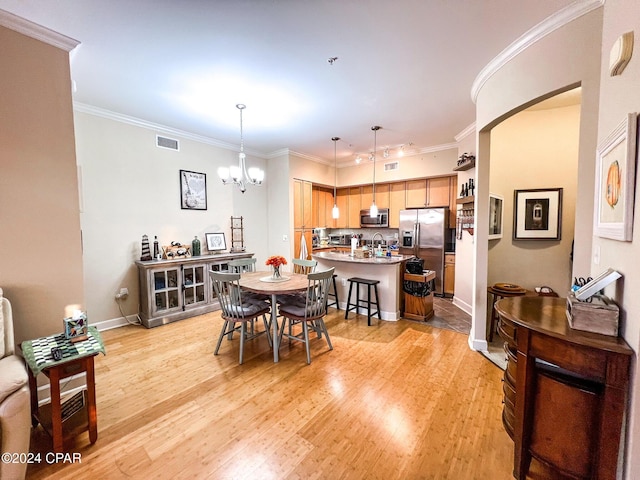 dining room featuring crown molding, an inviting chandelier, and light hardwood / wood-style flooring