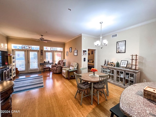 dining space featuring ceiling fan with notable chandelier, light hardwood / wood-style flooring, ornamental molding, and french doors