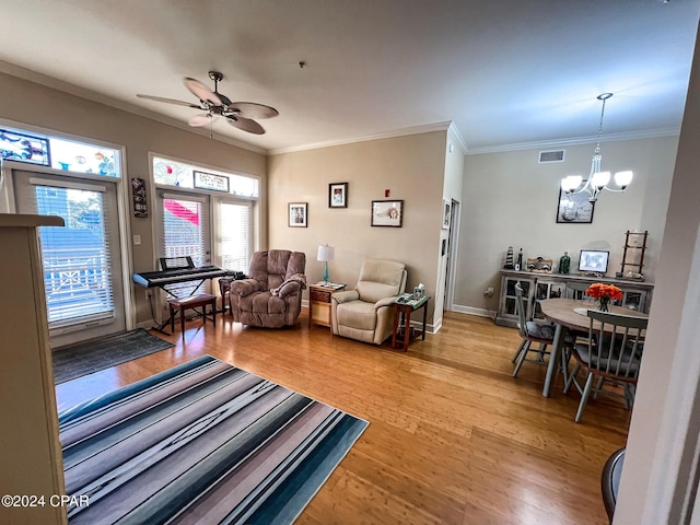 living room featuring wood-type flooring, ceiling fan with notable chandelier, and ornamental molding