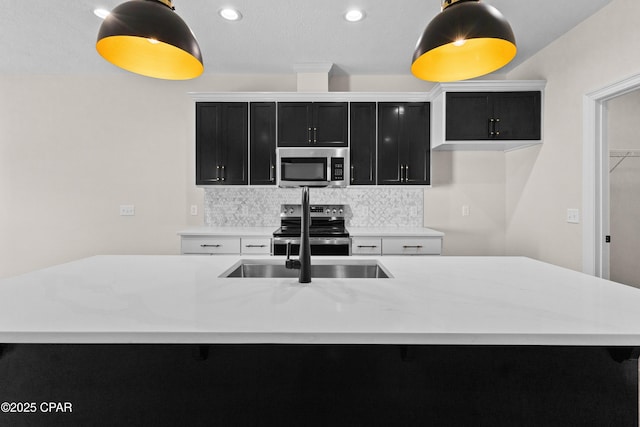 kitchen featuring sink, appliances with stainless steel finishes, tasteful backsplash, white cabinets, and a center island with sink