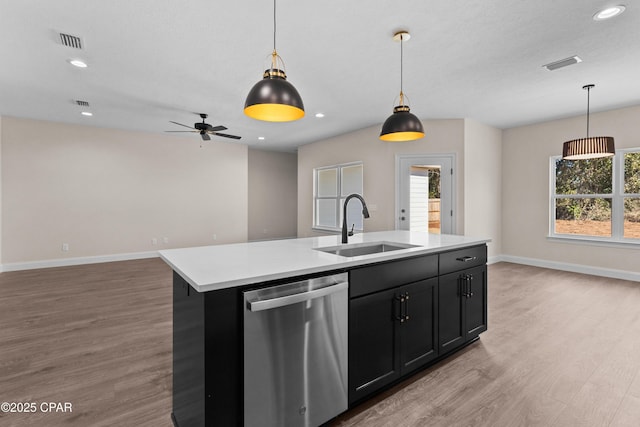 kitchen featuring sink, decorative light fixtures, stainless steel dishwasher, and a center island with sink