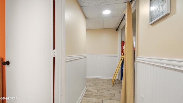 hall featuring a paneled ceiling and light wood-type flooring