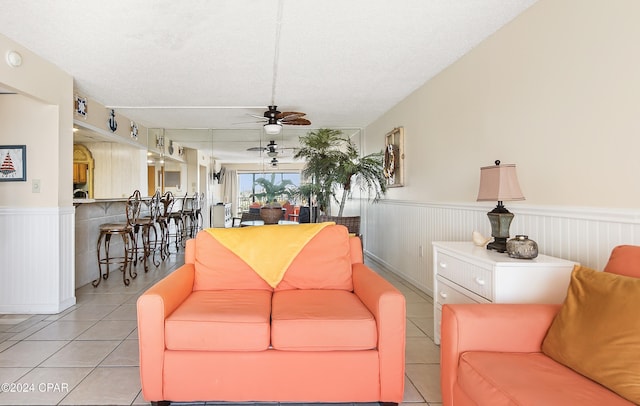 living room with ceiling fan, light tile patterned floors, and a textured ceiling