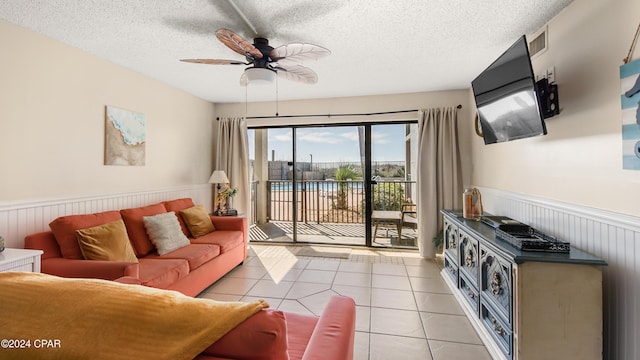 living room featuring ceiling fan, light tile patterned floors, and a textured ceiling