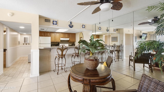 dining room featuring ceiling fan, light tile patterned floors, and a textured ceiling