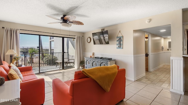 living room featuring ceiling fan, light tile patterned flooring, and a textured ceiling