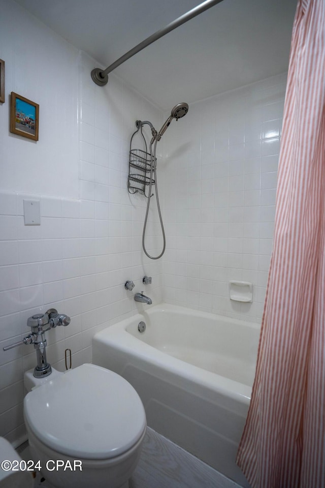 bathroom featuring toilet, shower / bathtub combination with curtain, and tile walls