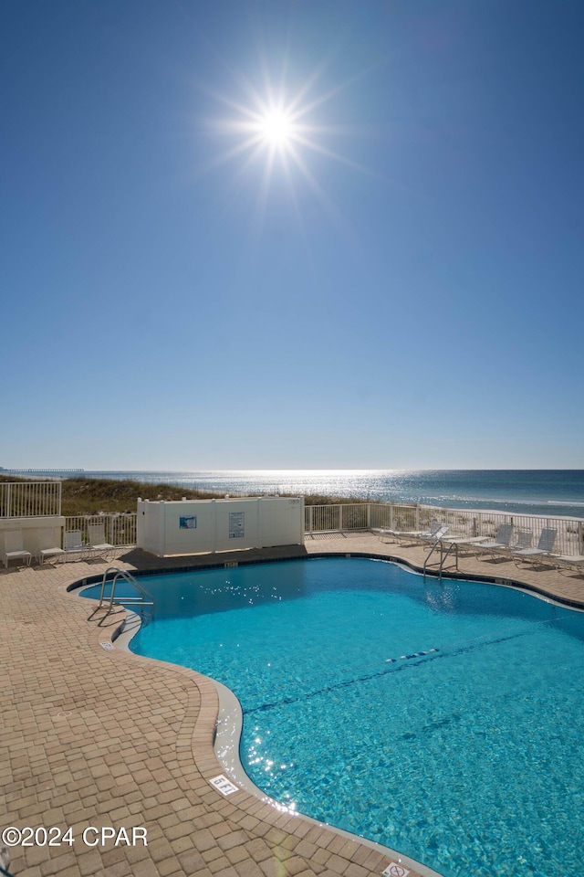 view of swimming pool with a water view and a patio