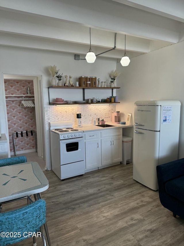 kitchen with pendant lighting, white appliances, sink, hardwood / wood-style flooring, and white cabinetry