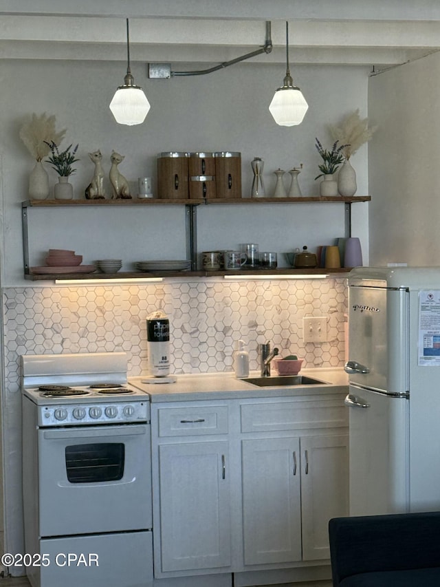 kitchen featuring white cabinets, white appliances, hanging light fixtures, and sink