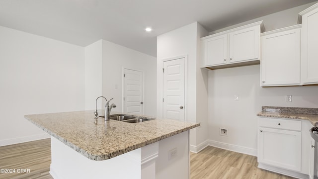 kitchen featuring white cabinetry, sink, an island with sink, and light wood-type flooring