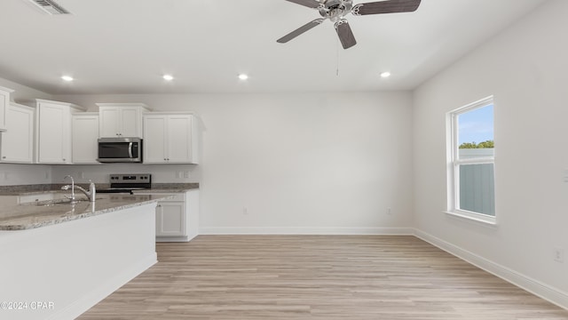 kitchen with light stone counters, sink, light hardwood / wood-style floors, white cabinetry, and range with electric stovetop