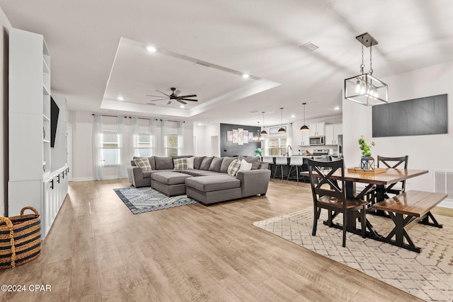 living room featuring a tray ceiling, a wealth of natural light, and light hardwood / wood-style floors