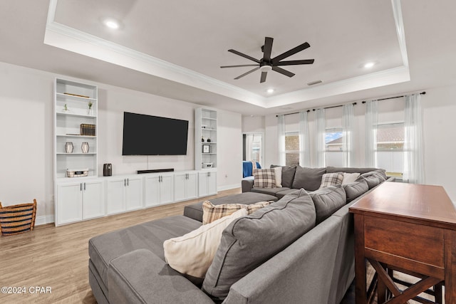 living room featuring a raised ceiling, a wealth of natural light, ceiling fan, and light hardwood / wood-style floors