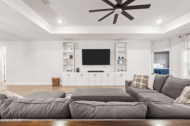 living room with a raised ceiling, ceiling fan, light hardwood / wood-style floors, and ornamental molding