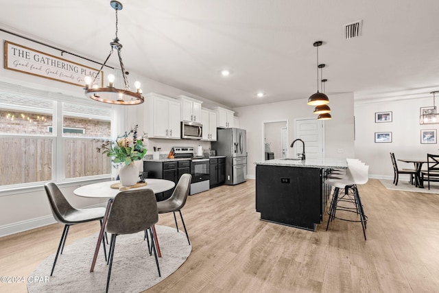 dining room featuring sink, an inviting chandelier, and light wood-type flooring