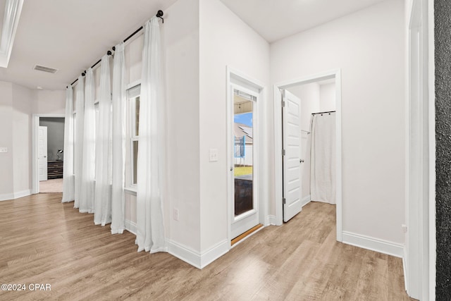 hall with plenty of natural light and light hardwood / wood-style floors