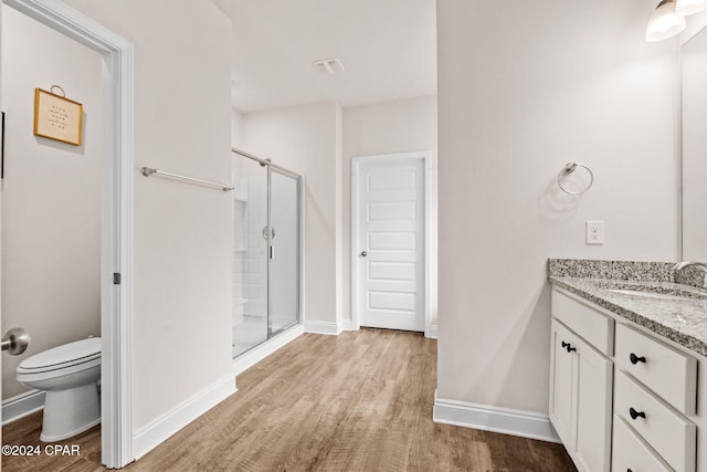 bathroom featuring wood-type flooring, vanity, toilet, and a shower with door