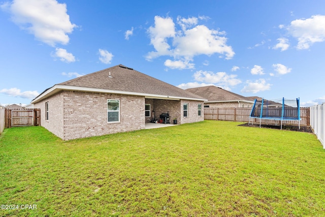 rear view of house with a lawn, a patio, and a trampoline