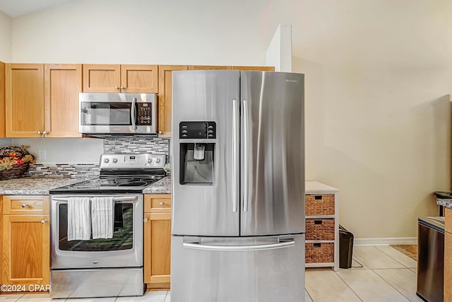 kitchen with tasteful backsplash, light tile patterned floors, appliances with stainless steel finishes, and vaulted ceiling