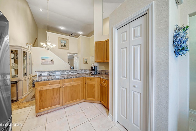 kitchen with stone counters, light tile patterned floors, a chandelier, and decorative light fixtures