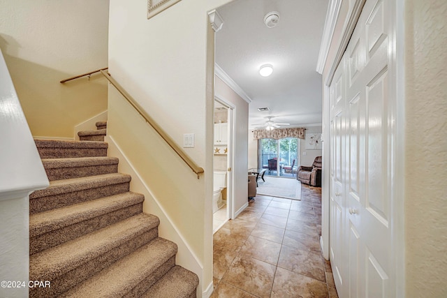 staircase with tile patterned floors, ceiling fan, and ornamental molding