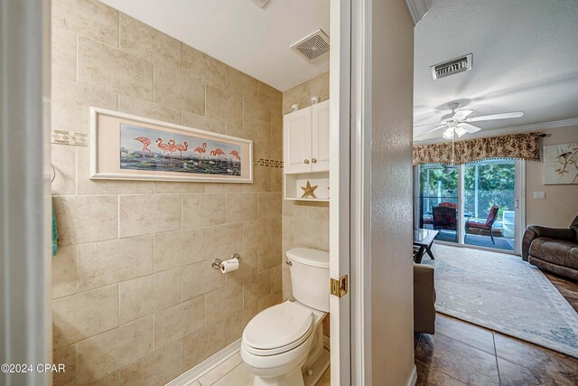 bathroom featuring crown molding, tile patterned flooring, ceiling fan, toilet, and tile walls