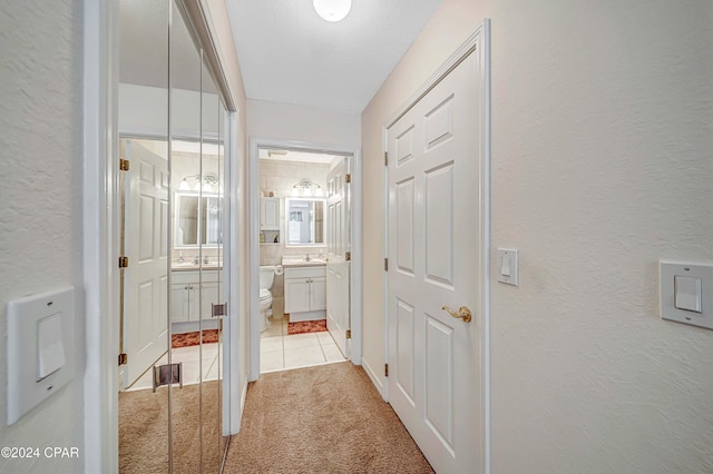 corridor featuring light colored carpet and sink