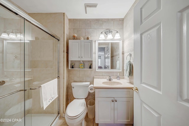 bathroom with vanity, an enclosed shower, tile walls, and toilet