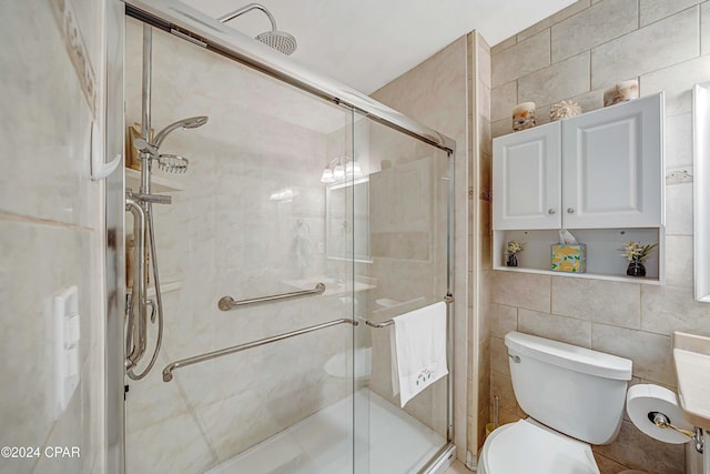 bathroom featuring a shower with shower door, tile walls, and toilet