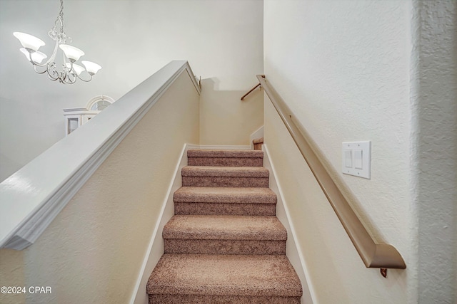 staircase with a chandelier