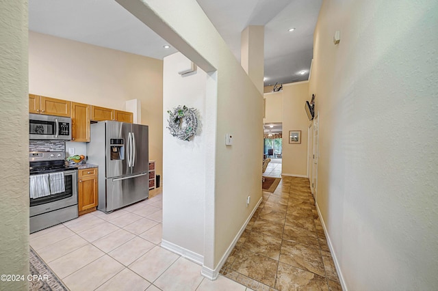 kitchen with appliances with stainless steel finishes, backsplash, and a high ceiling