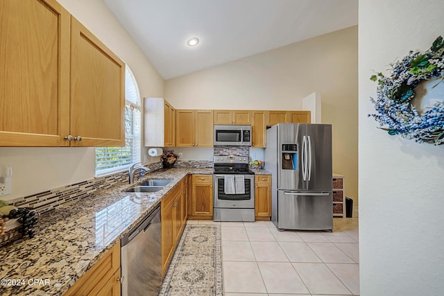 kitchen with stainless steel appliances, vaulted ceiling, sink, light tile patterned floors, and stone countertops