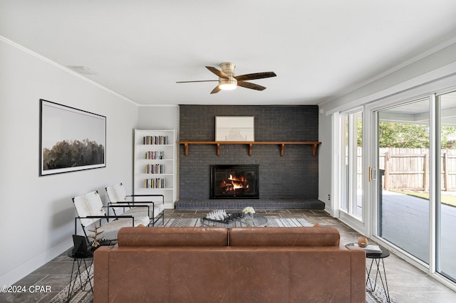 living room with a brick fireplace, ornamental molding, and ceiling fan