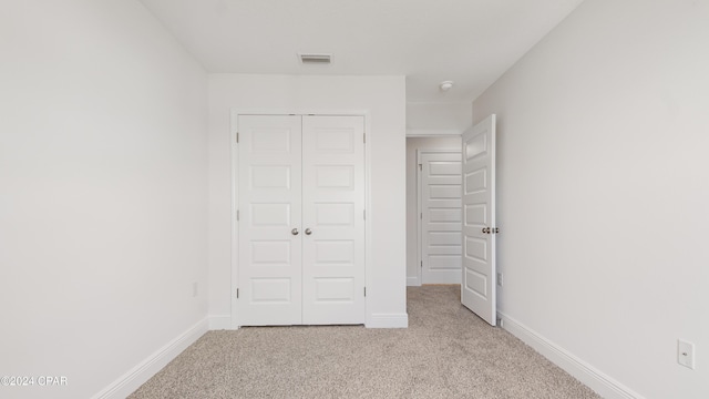 unfurnished bedroom with light colored carpet and a closet