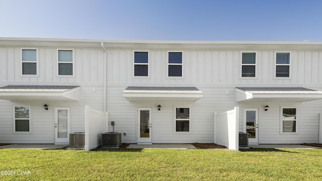 back of house with central AC unit and a lawn