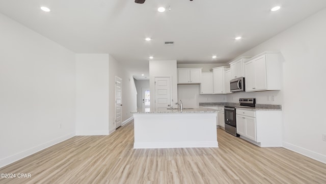 kitchen with white cabinets, appliances with stainless steel finishes, light hardwood / wood-style floors, and an island with sink